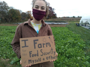 Addie King '21 holds a cardboard sign that reads "I farm for the food security for myself and others."